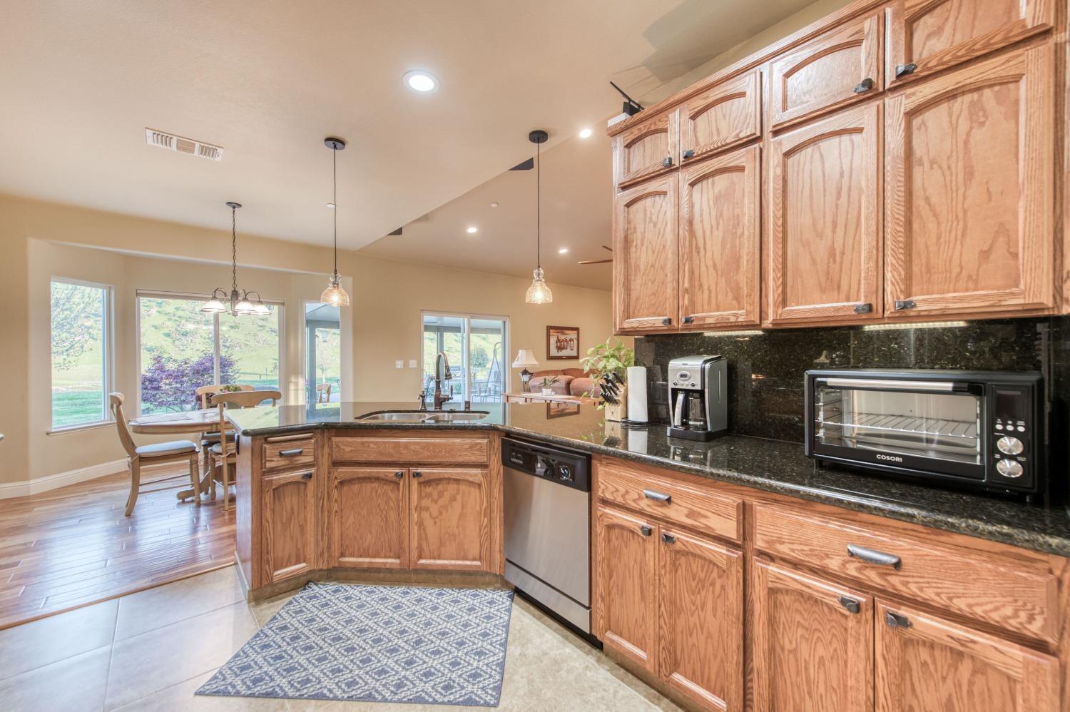 20431 Thermal Road Sanger, CA 93657 - Photo 15 of 88 a kitchen with stainless steel appliances kitchen island granite countertop a refrigerator a sink dishwasher a dining table and chairs with wooden floor