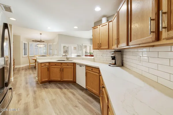 a kitchen with stainless steel appliances kitchen island granite countertop a stove a sink a refrigerator and white cabinets with wooden floor