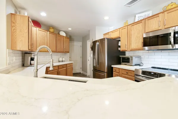 a kitchen with stainless steel appliances a sink a stove a microwave a refrigerator and cabinets