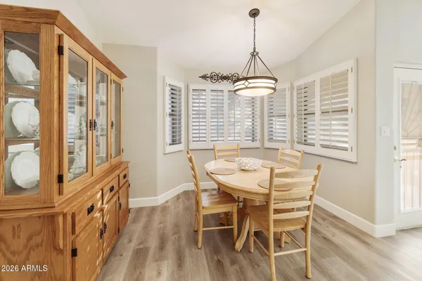 a dining room with wooden floor a chandelier a wooden table and chairs