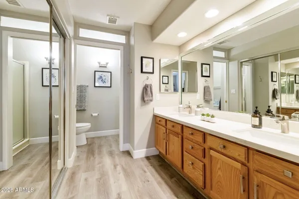 a spacious bathroom with a double vanity sink a mirror and a toilet