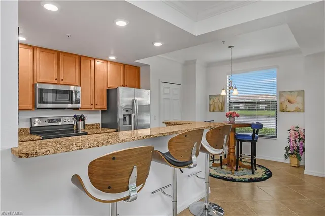 a kitchen with stainless steel appliances granite countertop a sink a stove a refrigerator cabinets and chairs