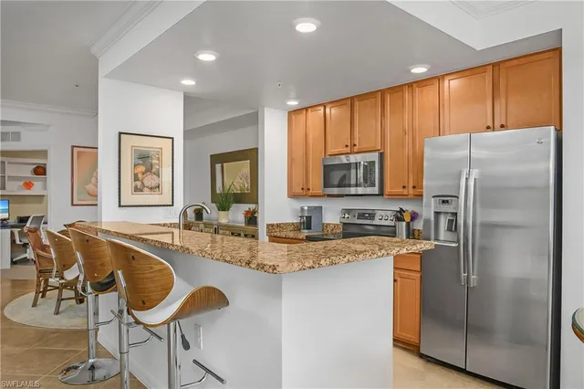 a kitchen with granite countertop a refrigerator oven a sink a dining table and chairs