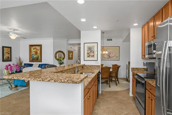 a view of a kitchen center island dining table wooden floor and stainless steel appliances