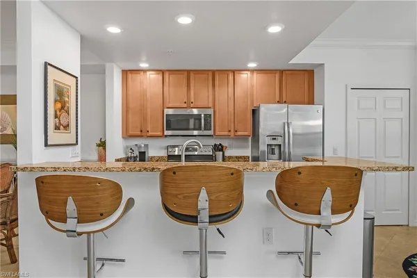 a kitchen with granite countertop a stove a sink a refrigerator with a dining table and chairs