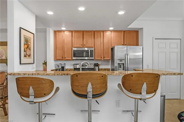 a kitchen with granite countertop a stove a sink a refrigerator with a dining table and chairs