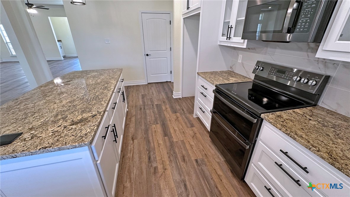 4237 Cool Basin Road Kempner, TX 76539 - Photo 7 of 36 a kitchen with wooden floors and a stove