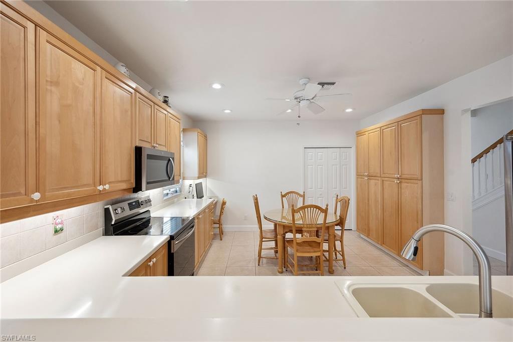 10082 Vanderbilt Drive Naples, FL 34108 - Photo 13 of 43 a kitchen with stainless steel appliances granite countertop a sink a stove and a refrigerator with wooden floor