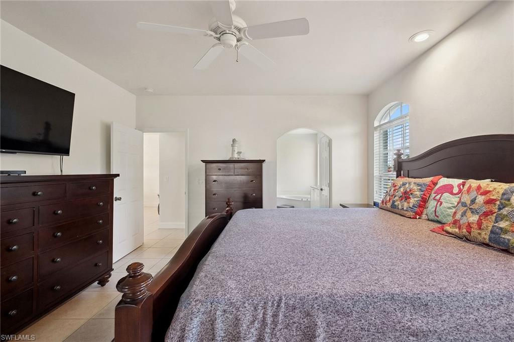 10082 Vanderbilt Drive Naples, FL 34108 - Photo 19 of 43 a spacious bedroom with a bed and a flat screen tv