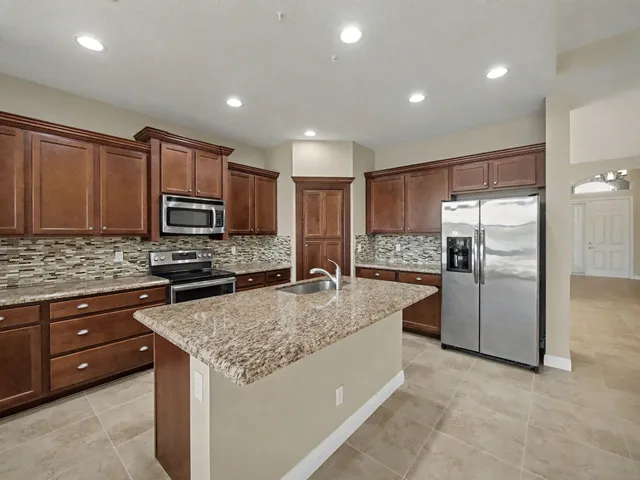 a large kitchen with granite countertop a large counter top stainless steel appliances and cabinets