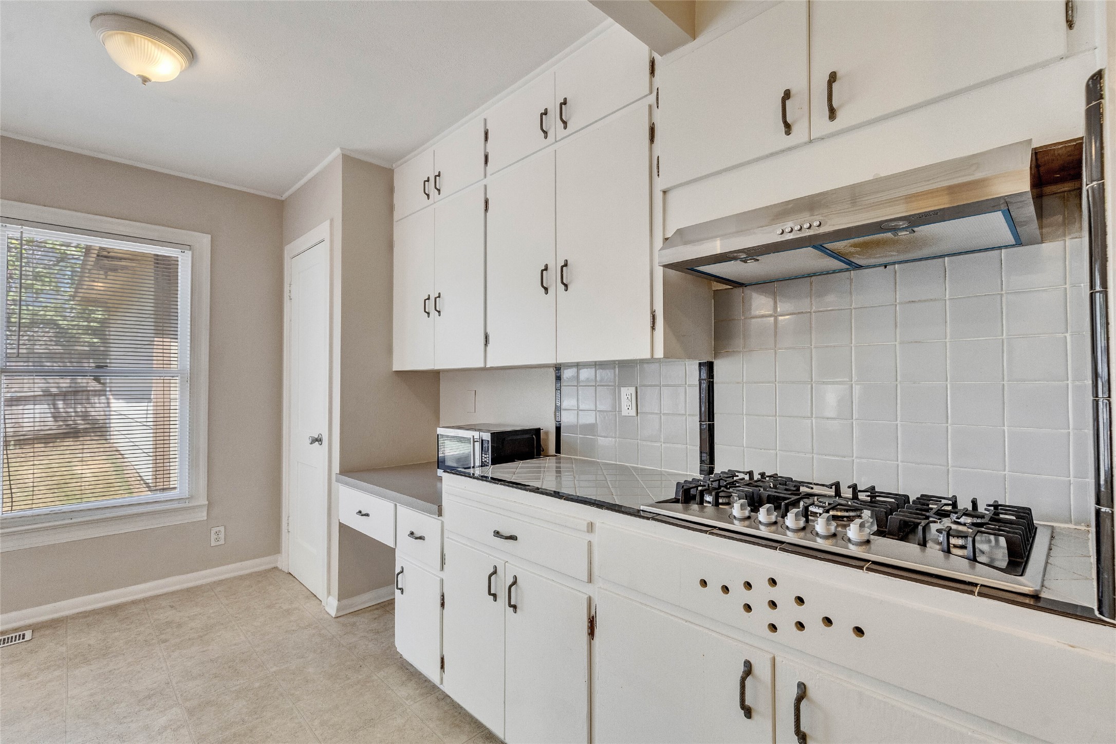 3810 Brookview Road Austin, TX 78722 - Photo 8 of 27 White cabinetry, tile backsplashes, and integrated cooking surfaces define this classic kitchen layout.