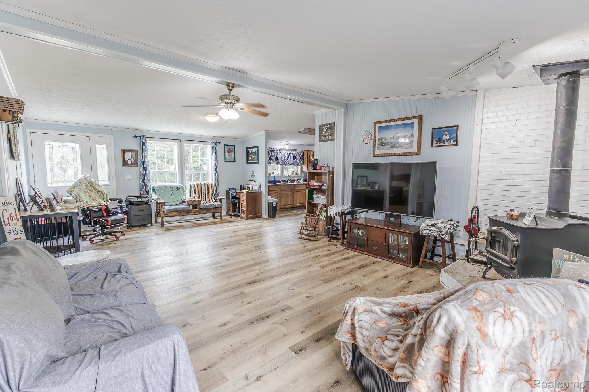 2649 Brown Road Millington, MI 48746 - Photo 5 of 18 Spacious interior featuring wood-finish flooring, a white brick accent wall, and a black wood-burning stove