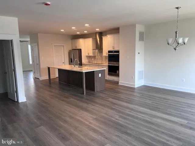 a kitchen with stainless steel appliances a kitchen island hardwood floor and a sink