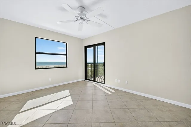 a view of an empty room with chandelier fan and a window