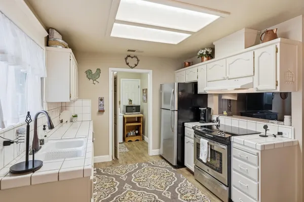 a view of kitchen with sink stainless steel appliances and cabinets