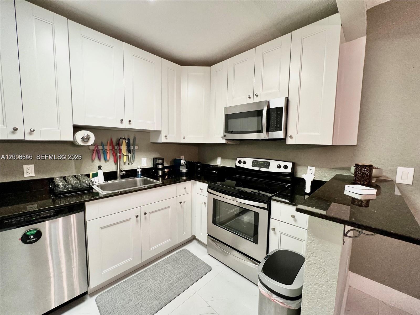 1380 Southwest 11th Street, Unit 1 Miami, FL 33135 - Photo 4 of 20 a kitchen with granite countertop white cabinets sink and stainless steel appliances