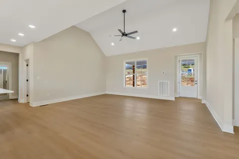 an empty room with wooden floor ceiling fan and windows