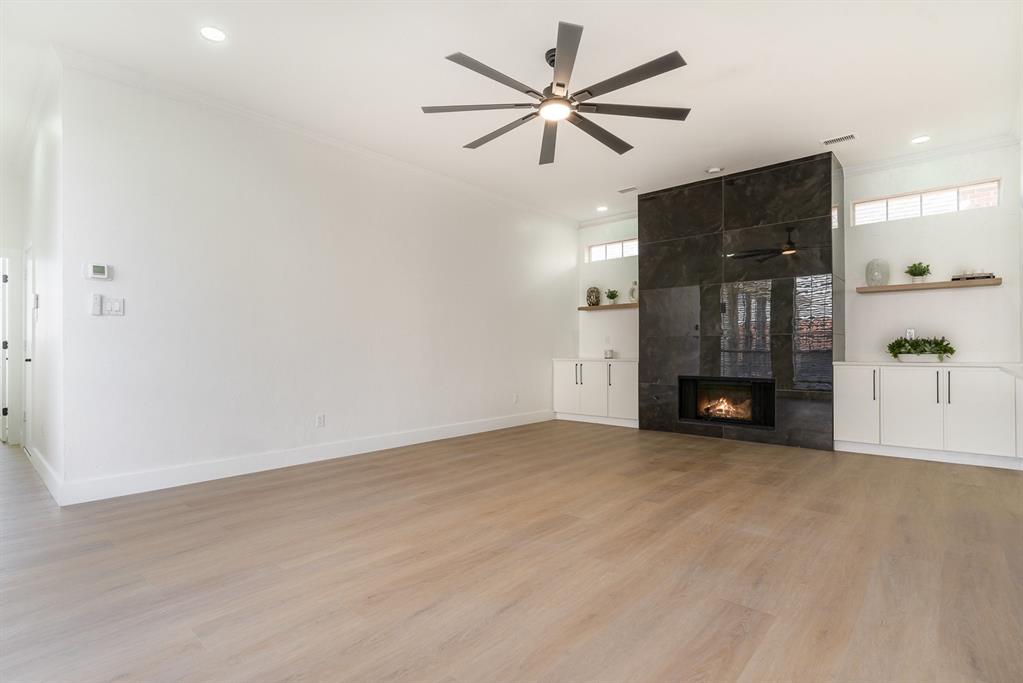 7524 Aberdon Road Dallas, TX 75252 - Photo 11 of 39 Unfurnished living room featuring ornamental molding, light wood-style floors, a fireplace, and ceiling fan