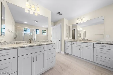 a bathroom with a granite countertop double vanity sink and mirror