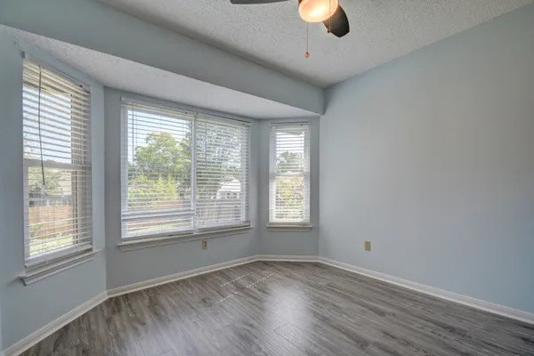 a view of an empty room with window and wooden floor