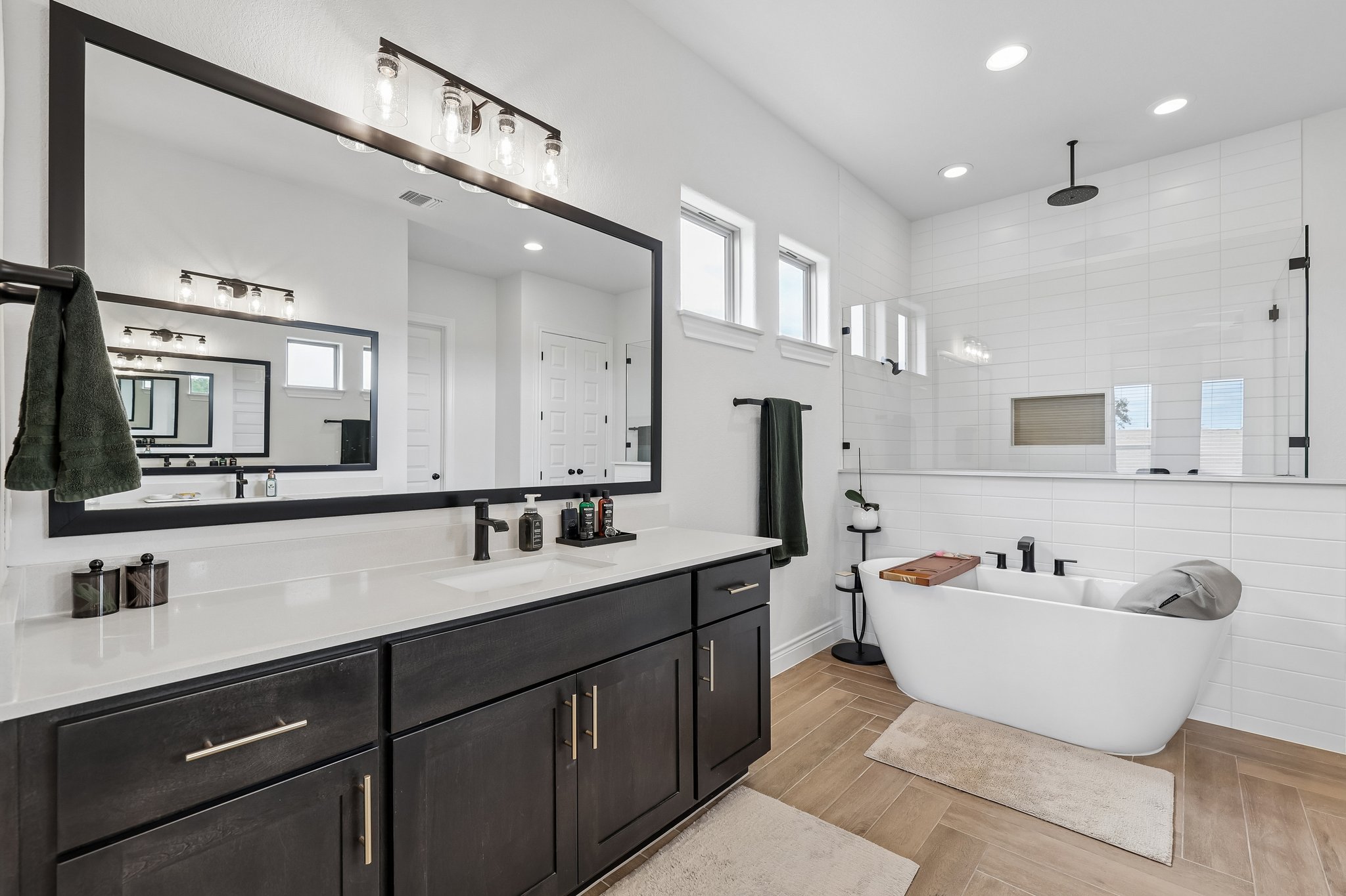 130 Firethorn Loop Bastrop, TX 78602 - Photo 22 of 38 Modern bathroom featuring a double vanity with dark wood cabinetry, white countertops, and a large framed mirror