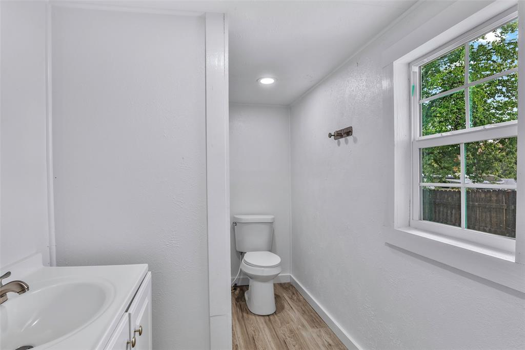 1005 North Neal Street Commerce, TX 75428 - Photo 9 of 23 a bathroom with a toilet a sink and a window