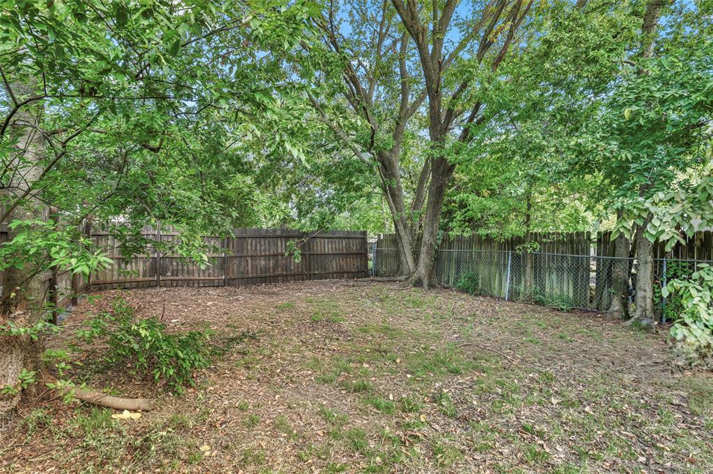1005 North Neal Street Commerce, TX 75428 - Photo 10 of 23 a backyard of a house with large trees and wooden fence