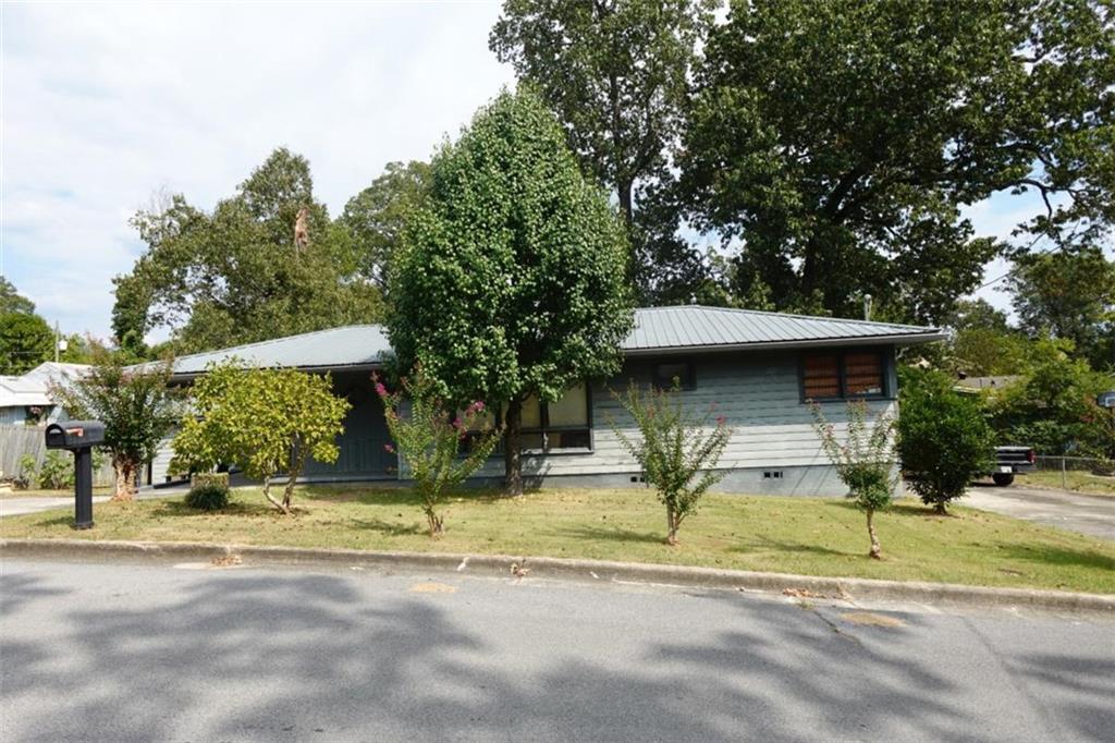 a view of a house with a yard and a large tree