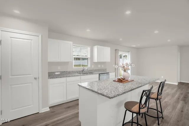 a living room with kitchen island granite countertop wooden floor and a couch