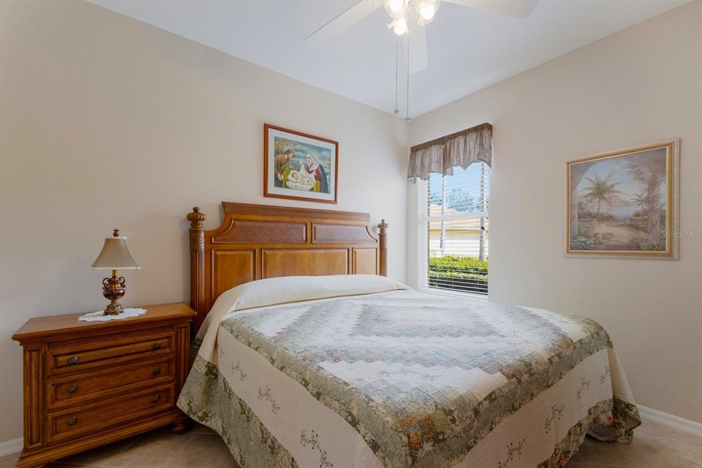 8414 Wethersfield Run, Unit 102 Lakewood Ranch, FL 34202 - Photo 24 of 48 a bedroom with a bed and a chandelier