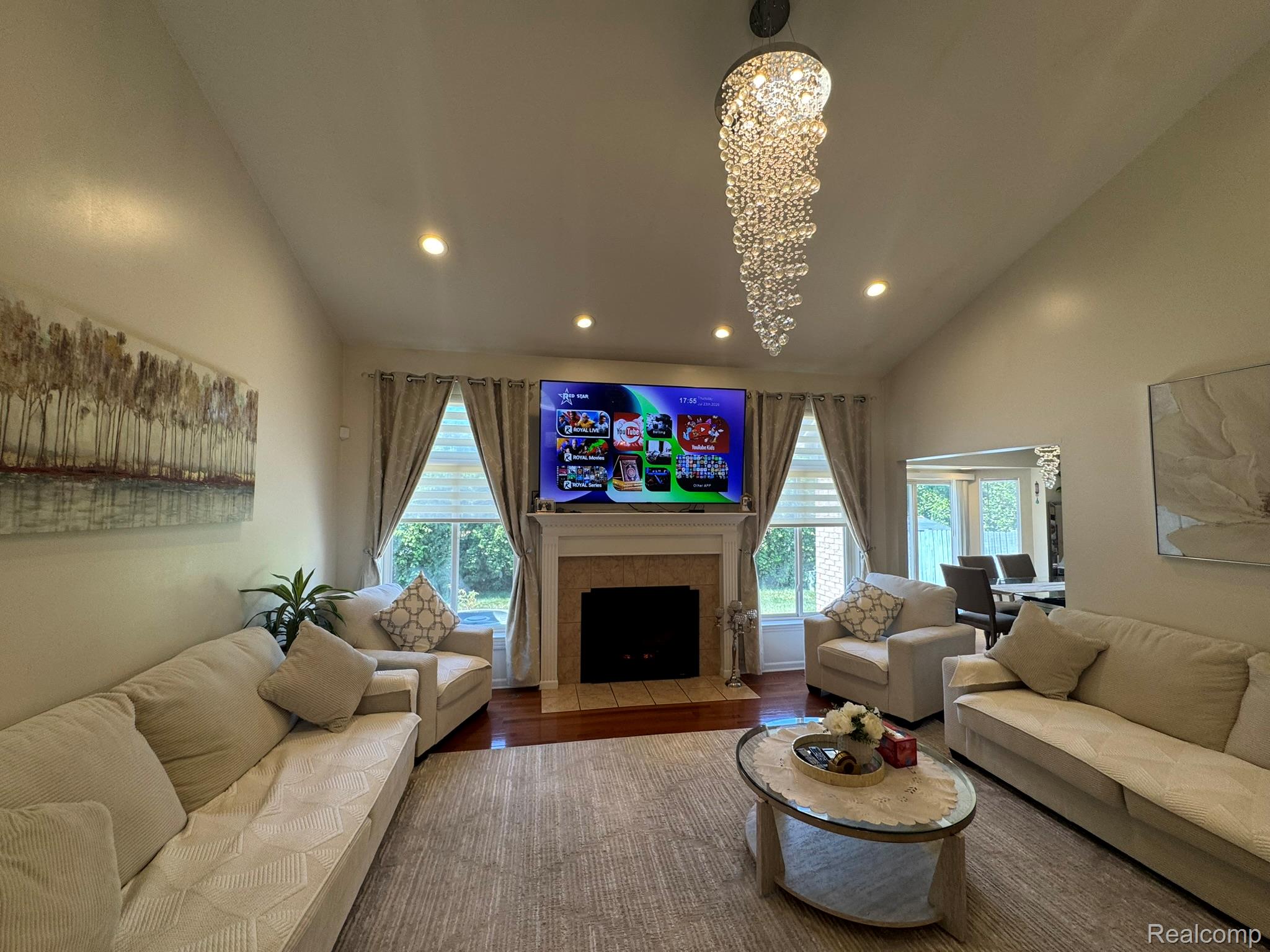 324 Cherry Lane Inkster, MI 48141 - Photo 8 of 28 Vaulted ceiling living area featuring a large fireplace with a stone surround, recessed lighting, and a prominent crystal chandelier