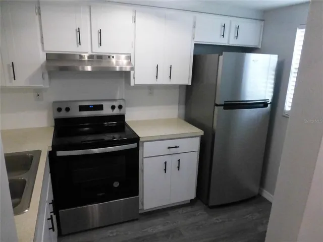 a kitchen with stainless steel appliances a stove a refrigerator and cabinets