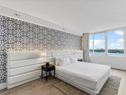 a bedroom with a large white bed and a large window