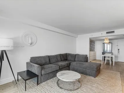 a living room with furniture and a dining table with wooden floor
