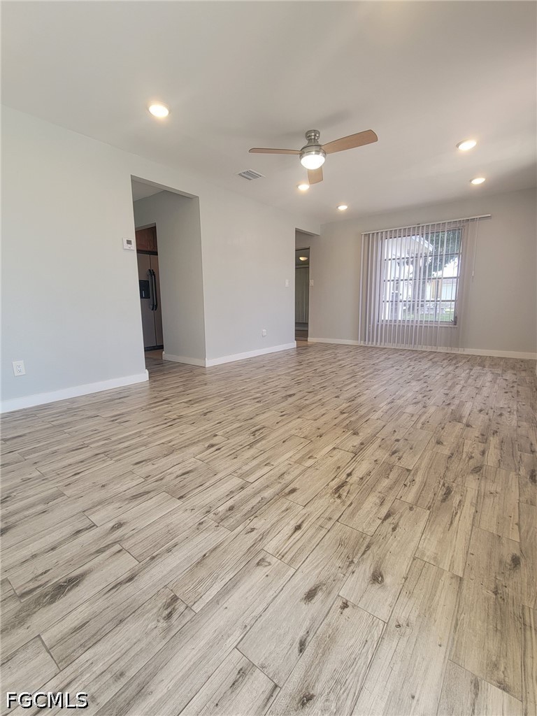 47 Tangelo Court Lehigh Acres, FL 33936 - Photo 5 of 18 an empty room with wooden floor and windows