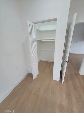 a view of an empty room with wooden floor and closet