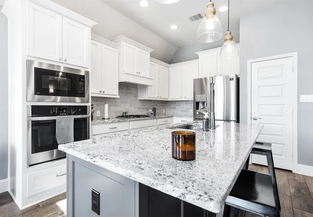 a kitchen with stainless steel appliances granite countertop a sink stove microwave and refrigerator