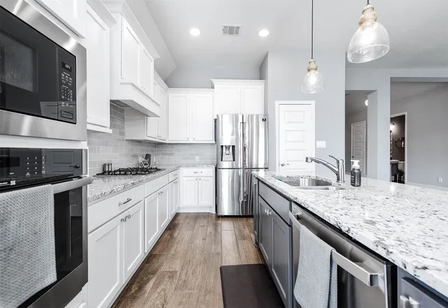 a large kitchen with stainless steel appliances granite countertop a lot of counter space and wooden floor