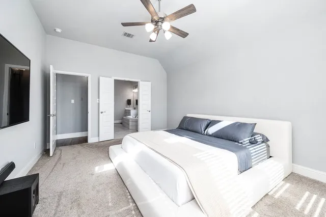 a spacious bedroom with a bed and a chandelier