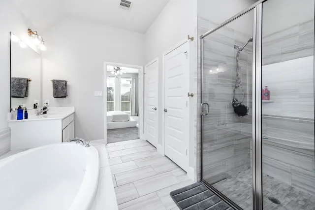 a bathroom with a tub shower sink and mirror