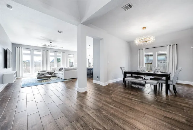 a living room with furniture a large window and wooden floor