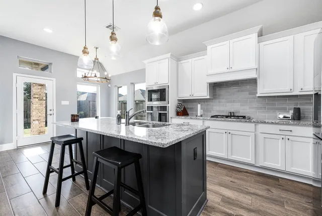 a kitchen with granite countertop white cabinets and chairs