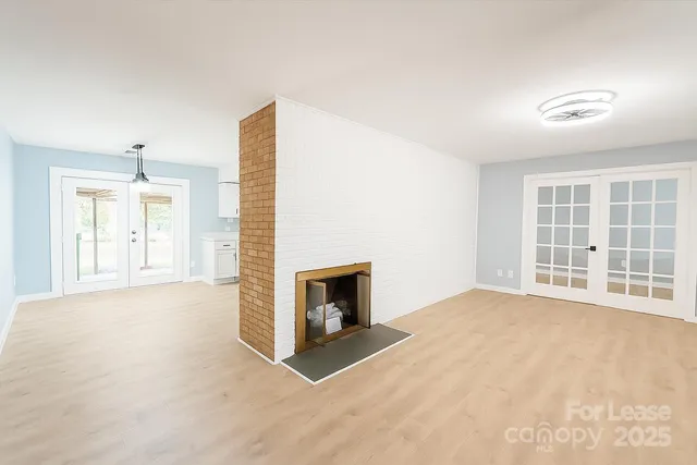 an empty room with windows and fireplace