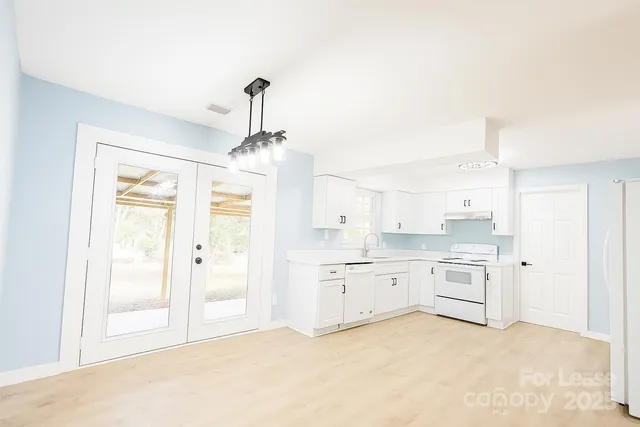 a large kitchen with white cabinets and stainless steel appliances