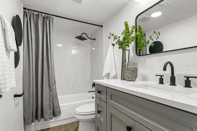 a bathroom with a granite countertop sink a toilet and shower