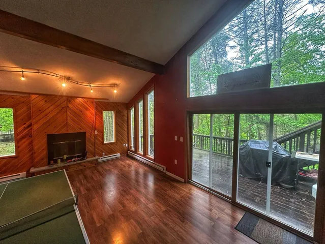 a view of an empty room with wooden floor and a fireplace