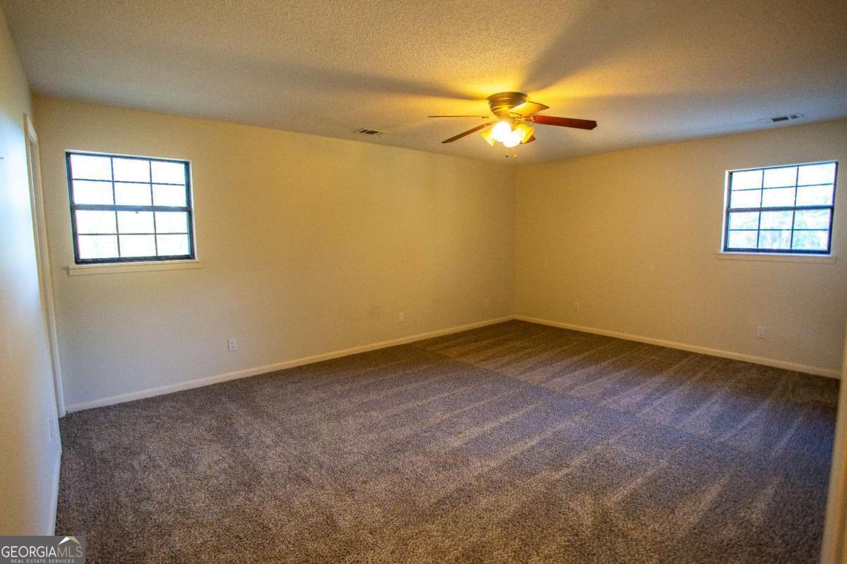 528 Gardner Road Baxley, GA 31513 - Photo 33 of 39 an empty room with a chandelier fan and windows