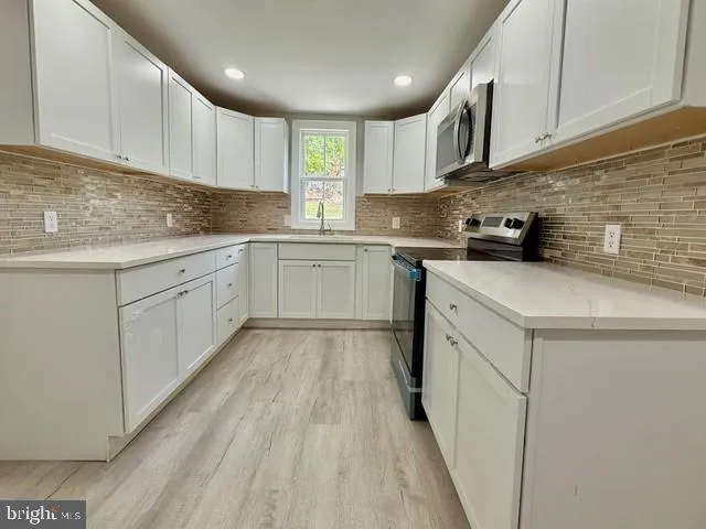 a kitchen with cabinets appliances a sink and a counter top space