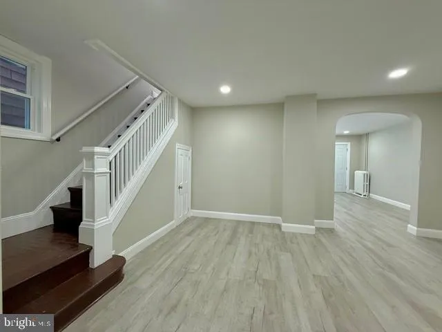 a view of an empty room with wooden floor and stairs