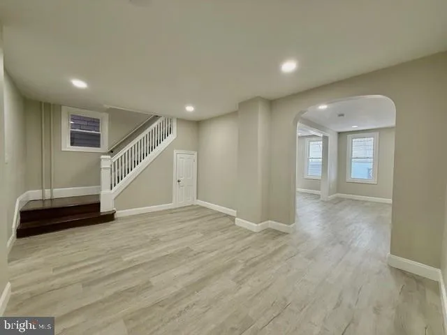a view of an empty room with wooden floor and stairs